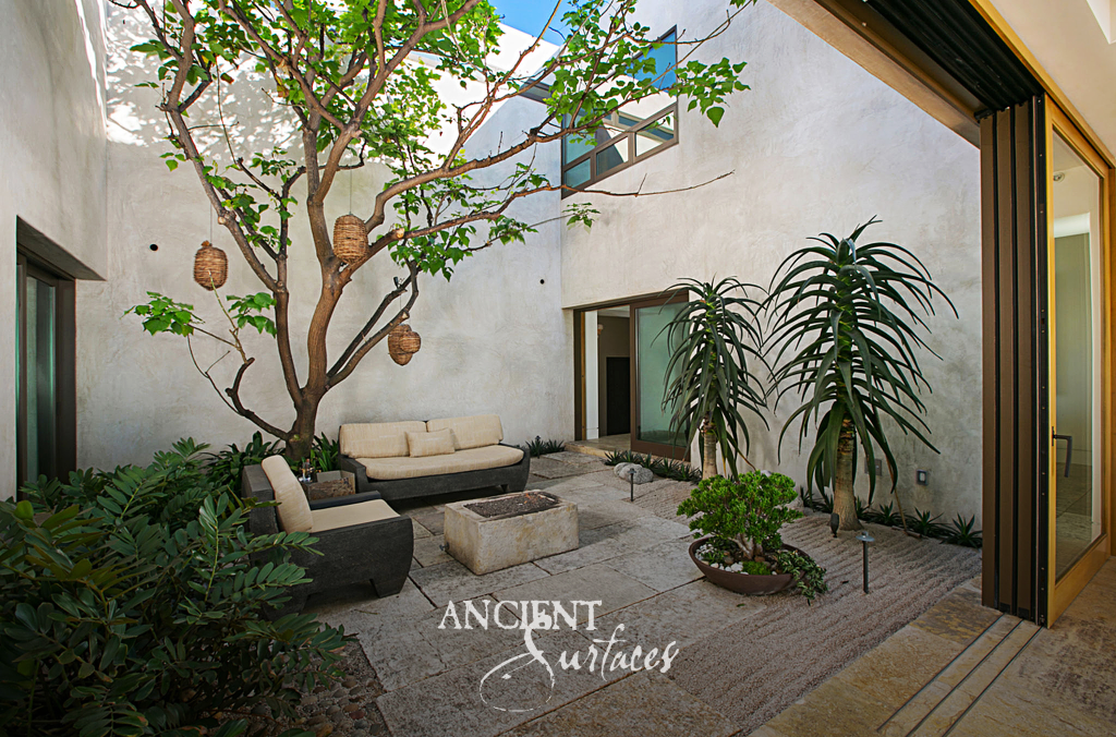 Sheltered courtyard floored in reclaimed limestone around a mature tree and a weathered stone trough
