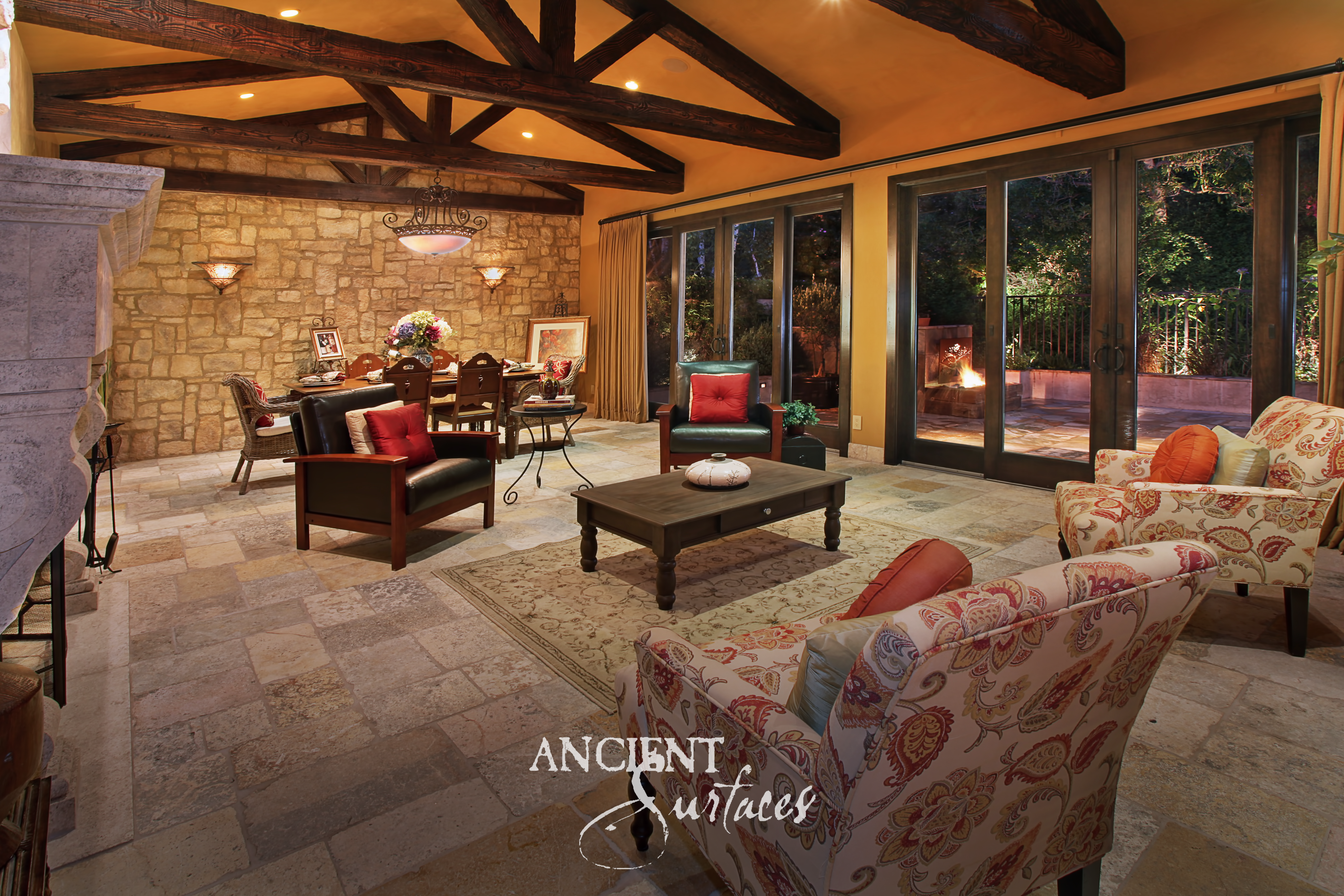 Beamed living room with reclaimed limestone flooring, a limestone clad wall, and a carved stone fireplace