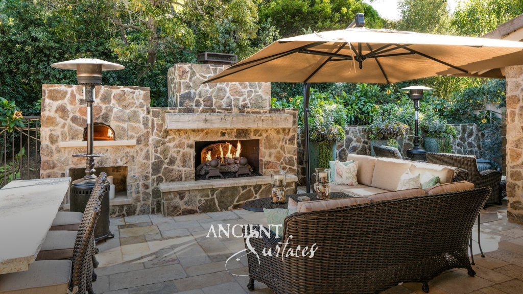 Patio paved in reclaimed limestone around a sculptural limestone masonry fireplace and a wood fired oven