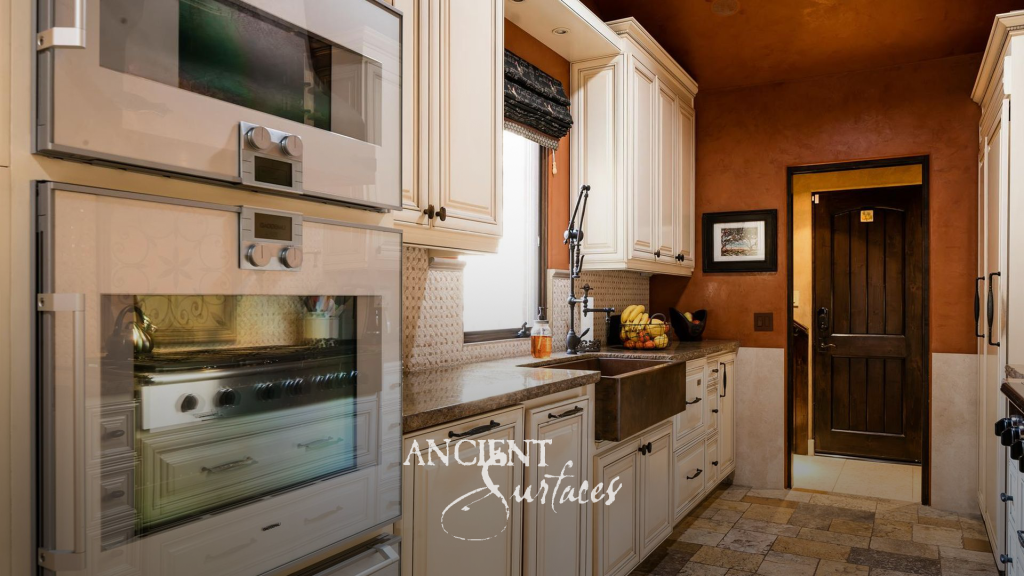 Kitchen with a hammered copper farmhouse sink and reclaimed limestone flooring running to the pantry door