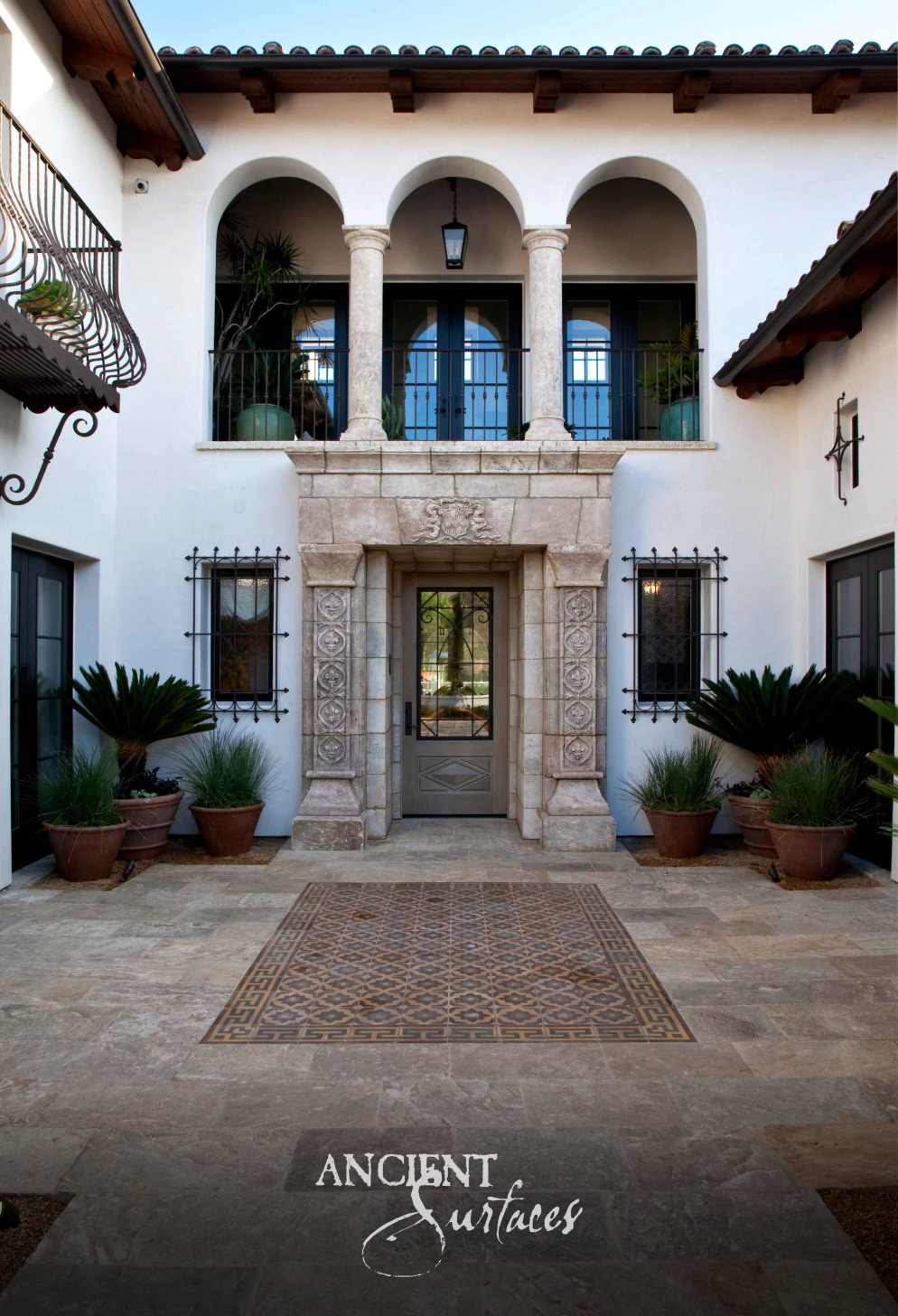 Entry courtyard paved in Kronos limestone with an inset stone mosaic square below a carved surround and colonnaded loggia