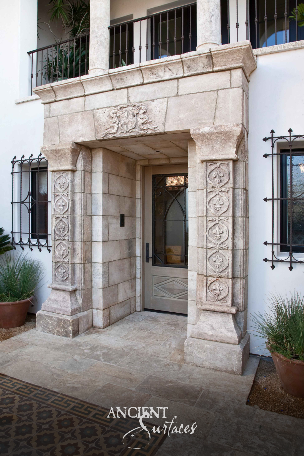 Hand carved Kronos limestone entry surround with a sculpted crest and pilasters cut with rosettes and fleur de lis motifs