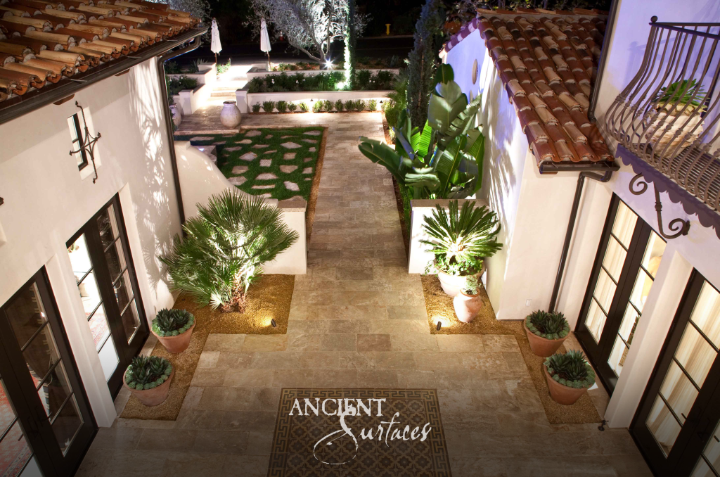 Kronos limestone courtyard seen from above at night, laid in mixed formats around an inset mosaic and planter copings